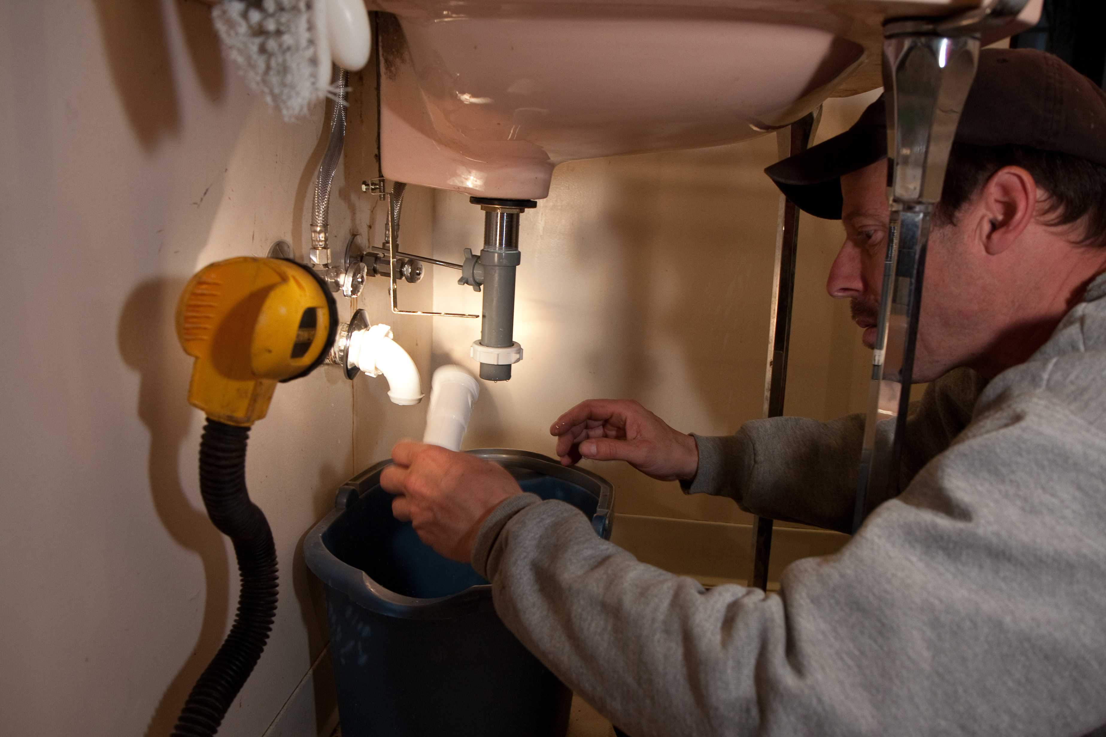 Plumber working on the water pipes beneath a sink